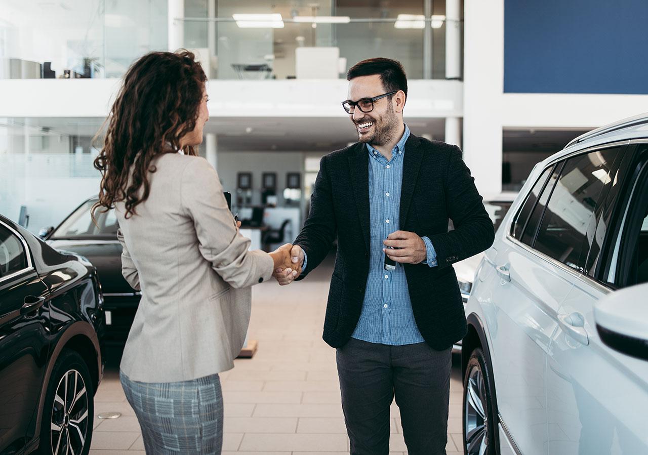 One man and one woman shaking heads at a car dealership